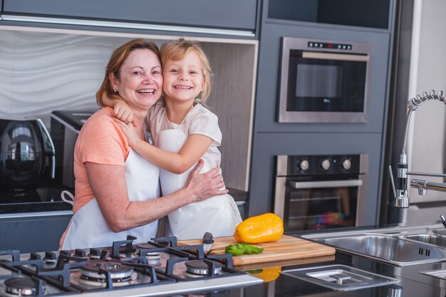 Buona festa della mamma! Figlia bambina e mamma che cucinano e si divertono in cucina a casa. Vacanza in famiglia e stare insieme.