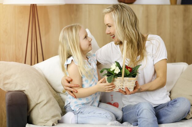 Buona festa della mamma. La figlia del bambino si congratula con la mamma e le dà il cesto di fiori primaverili. Concetto di famiglia.