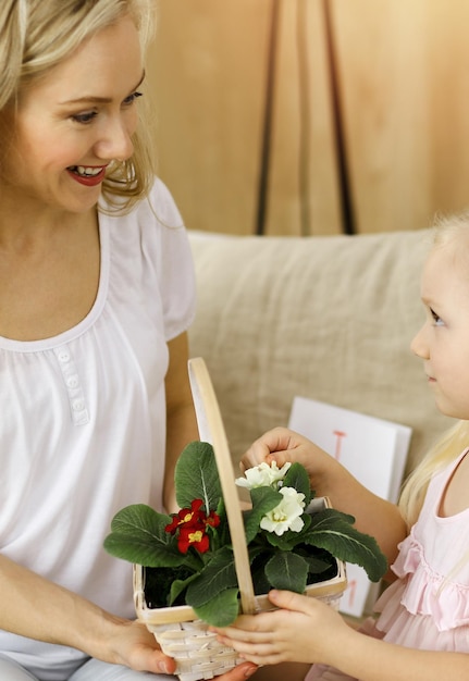 Buona festa della mamma. La figlia del bambino si congratula con la mamma e le dà il cesto di fiori primaverili. Concetto di famiglia.