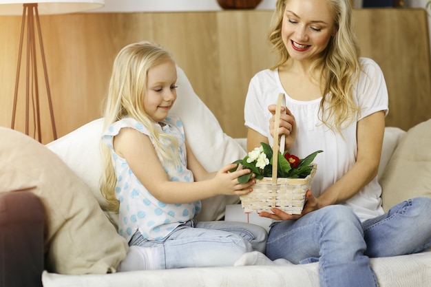 Buona festa della mamma. La figlia del bambino si congratula con la mamma e le dà il cesto di fiori primaverili. Concetto di famiglia.