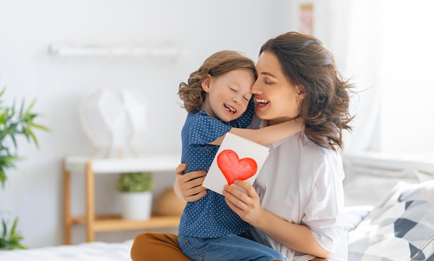 Buona festa della mamma La figlia del bambino si congratula con la mamma e le dà la cartolina