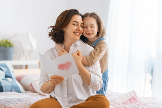 Buona festa della mamma La figlia del bambino si congratula con la mamma e le dà la cartolina