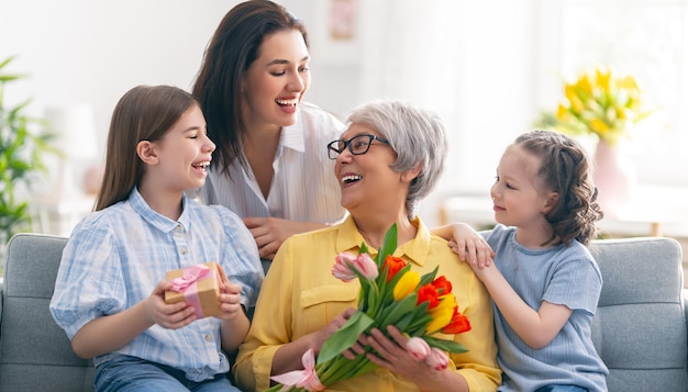 Buona festa della mamma Le figlie e la madre del bambino si congratulano con la nonna dando i suoi fiori tulipani