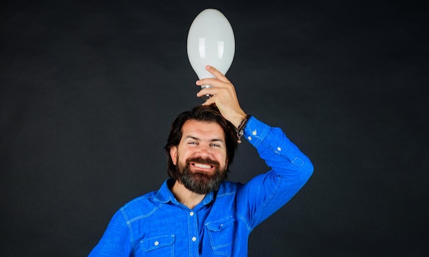 Buona idea bell'uomo barbuto in camicia di jeans con energia ed elettricità della lampadina