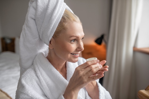 Buona mattinata. Una donna vestita di bianco guardando la finestra e prendendo il suo tè del mattino