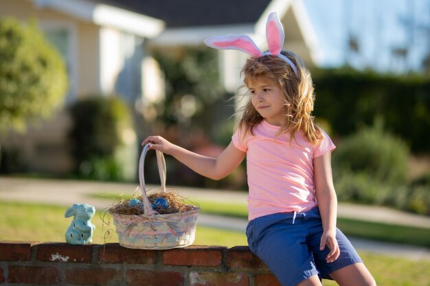 Buona Pasqua Bambini in orecchie da coniglio con uovo di Pasqua nel carrello Ragazzo gioca a caccia di uova Vacanze di Pasqua