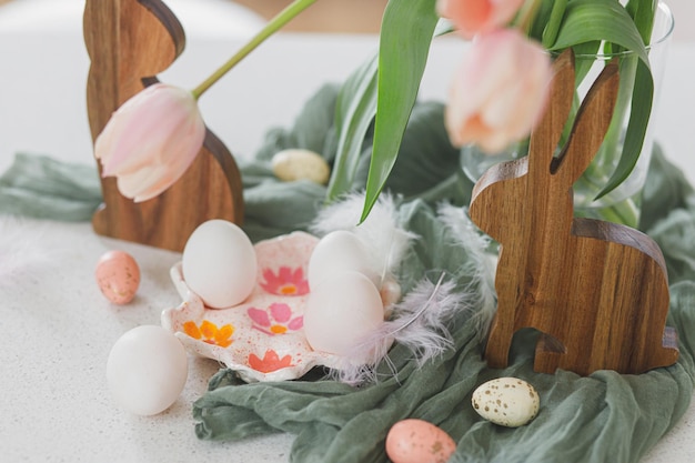Buona Pasqua Bellissimi tulipani uova naturali e decorazione coniglietto sul tavolo moderno Elegante arredamento pasquale in fattoria Portauovo fatto a mano bouquet di tulipani rosa e coniglietti in legno