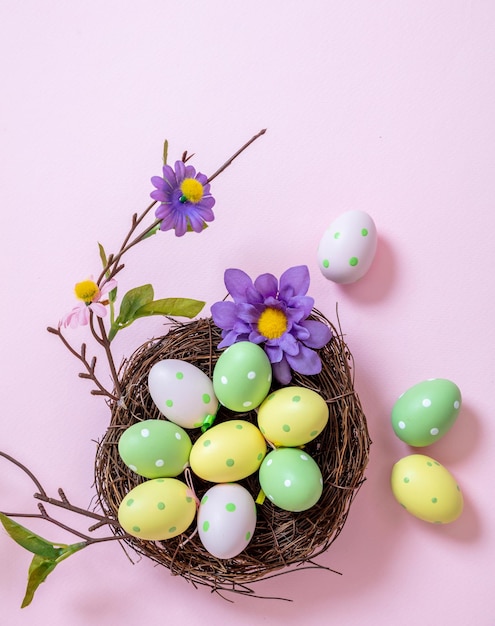 Buona Pasqua color pastello uova in un nido su sfondo rosa