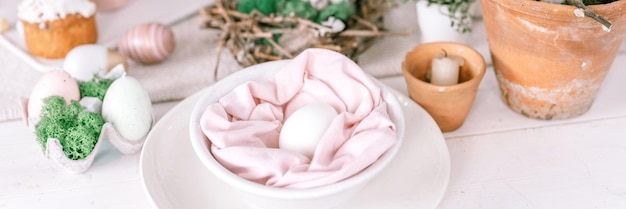 Buona pasqua e vacanze primaverili tempo festivo tablescape set arredamento cena tradizionale cibo uova di pasqua e torte al forno sul tavolo a casa coniglio e salice pallido pop pastello blu rosa colore banner