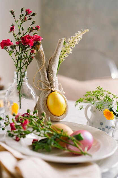 Buona Pasqua Eleganti uova di Pasqua su un tovagliolo con fiori primaverili su sfondo bianco in legno Tavola apparecchiata Il concetto di una felice vacanza di Pasqua