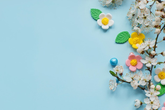 Buona Pasqua Fiori di caramelle di Pasqua e ramo di ciliegio in fiore piatto giacevano su sfondo blu Elegante modello festivo con spazio per il testo Biglietto di auguri o banner Festa della mamma