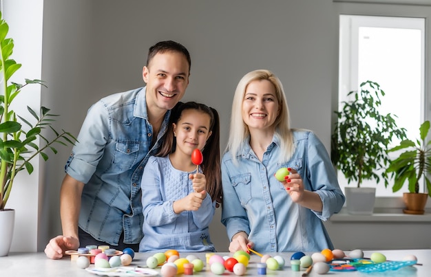 Buona Pasqua! madre di famiglia, padre e figli che si divertono a dipingere e decorare le uova per le vacanze.