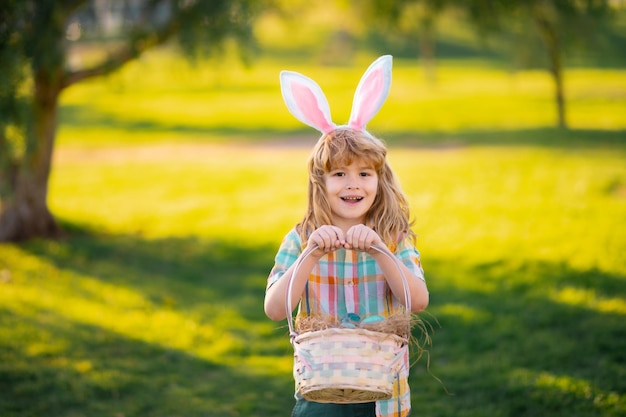 Buona pasqua per bambini bambino in costume da coniglio con orecchie da coniglio a caccia di uova di pasqua nel parco