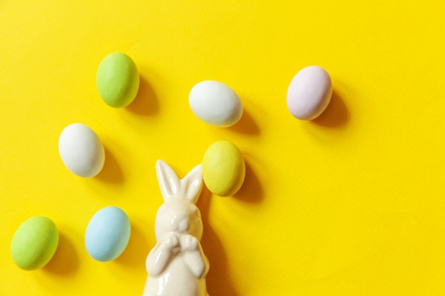 Buona Pasqua. Preparazione per le vacanze. Dolci e coniglietto delle uova di cioccolato della caramella di Pasqua isolati su fondo giallo d'avanguardia.