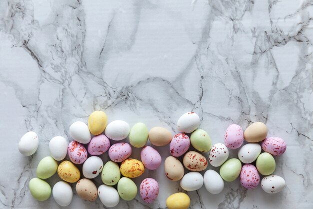 Buona Pasqua. Preparazione per le vacanze. Pasqua pastello caramelle uova di cioccolato dolci su marmo grigio alla moda. Semplice spazio minimalista piatto vista dall'alto copia spazio.