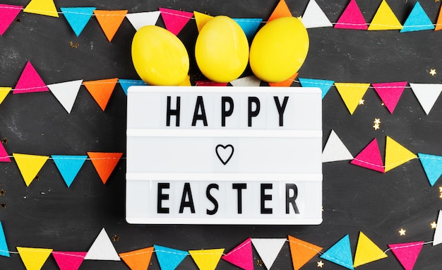 Buona Pasqua scritte sul bordo bianco con ghirlanda di feltro e uova dipinte di giallo su sfondo scuro
