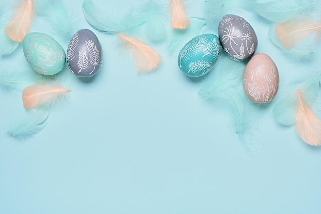 Buona Pasqua sfondo minimo Uova di Pasqua e piume su sfondo blu pastello Spazio per la copia piatta