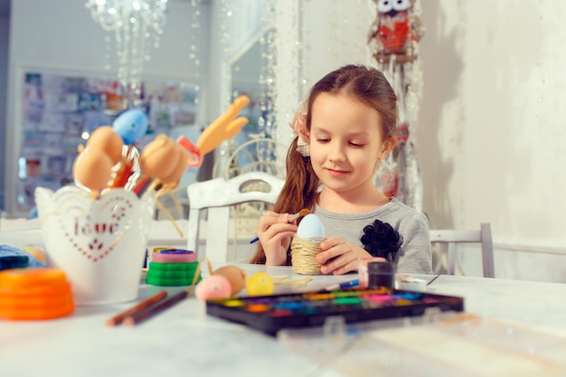 Buona Pasqua! Una ragazza del bello bambino che dipinge le uova di Pasqua. Famiglia felice che prepara per la Pasqua