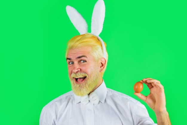 Buona Pasqua. Uomo barbuto in orecchie da coniglio con uovo di Pasqua. Uomo coniglio. Tempo di primavera. Caccia alle uova.