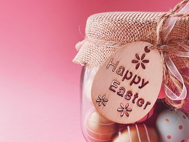 Buona Pasqua Uova di Pasqua colorate dipinte in barattolo di vetro su sfondo rosa Religione cristiana e concetto di vacanza