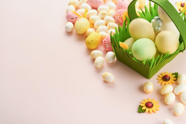 Buona Pasqua Uova di Pasqua e coniglio nel cesto verde su sfondo rosa con rose bianche e gialle Scheda di festa di buona Pasqua di primavera Sfondo di Pasqua con spazio di copia Vista dall'alto