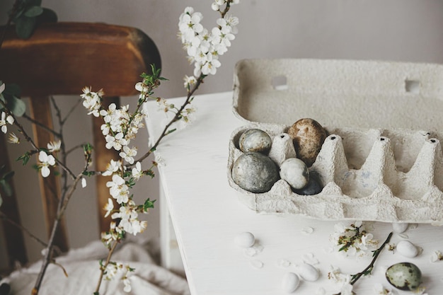Buona Pasqua Uova di Pasqua eleganti in vassoio e fiori di ciliegio su tavolo rustico Uova di marmo di colorante naturale moderno e fiori primaverili natura morta Composizione di Pasqua rurale