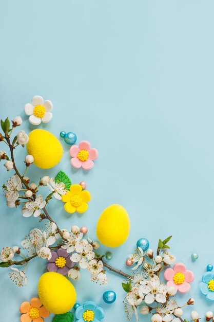 Buona Pasqua Uova di Pasqua fiori di caramella e ramo di ciliegio in fiore piatto adagiato su sfondo blu Elegante modello di pasqua con spazio per il testo Biglietto di auguri o banner