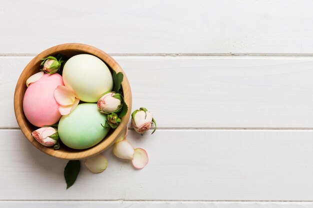 Buona Pasqua uova di Pasqua in cesto su tavolo colorato con rose gialle uova colorate naturali sfondo vista superiore con spazio di copia