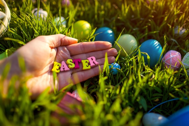 Buona Pasqua. Uova di Pasqua nascoste nell'erba primaverile. Scrittura fatta di lettere di legno in mano