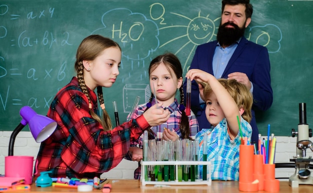 Buone notizie insegnante per bambini felici che fa esperimenti con liquidi in laboratorio di chimica laboratorio di chimica torna a scuola bambini in camice che imparano chimica nel laboratorio scolastico