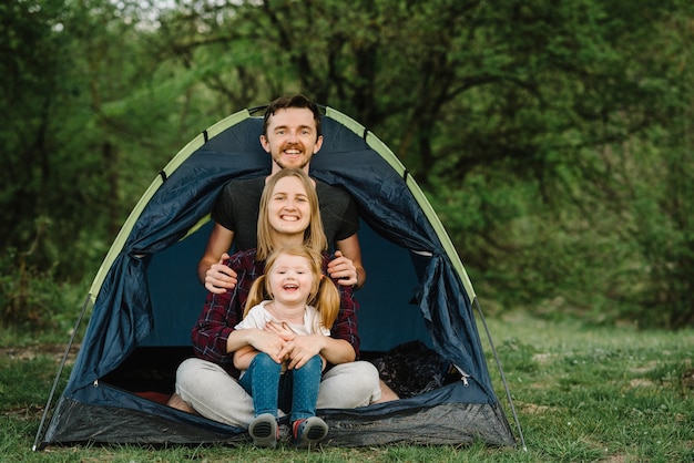 Buone vacanze in famiglia in tenda con un bambino nella natura. Ðoncept di vacanze estive e viaggi, viaggi. Campeggio. Mamma, papà abbraccia un bambino e si godono una vacanza in campeggio in campagna.