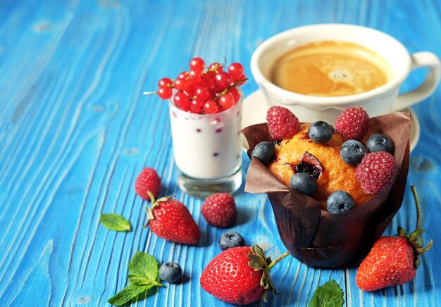 Buongiorno colazione Cupcake con frutti di bosco una tazza di caffè e yogurt con ribes rosso