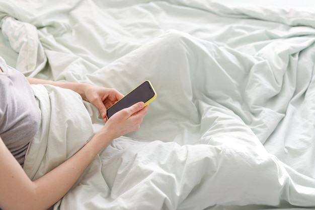 Buongiorno giornata di sole donna caucasica che controlla i messaggi con un telefono giallo in mano