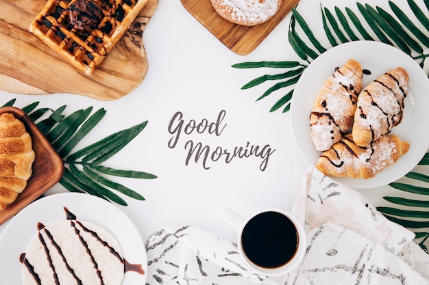 Buongiorno messaggio circondato da croissant al forno; cialde; focacce; tortillas e caffè su sfondo bianco