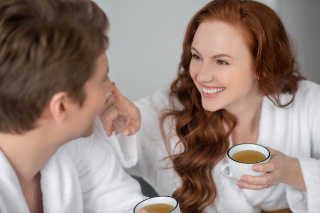 buongiorno. Una coppia in accappatoio bianco che beve caffè e si sente felice