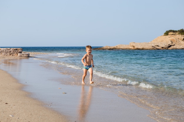 Buonumore. Ragazzo nel mare Infanzia in buona salute. Il ragazzo felice spruzza con acqua di mare. Divertente gioco in un clima caldo.