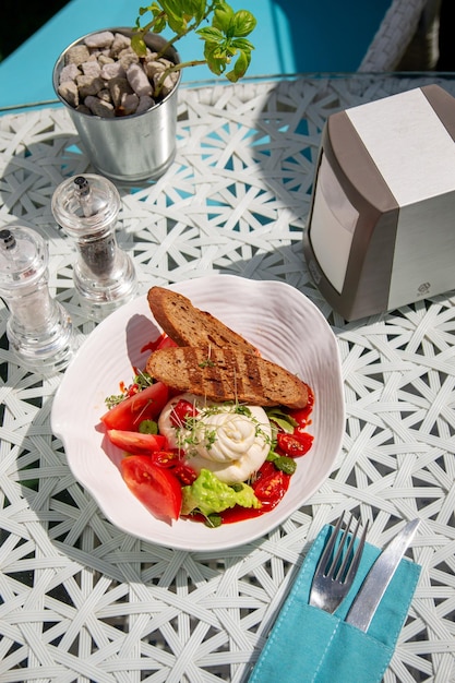 Burato e pomodoro rosso con crostini di crescione insalata e altre erbe verdi