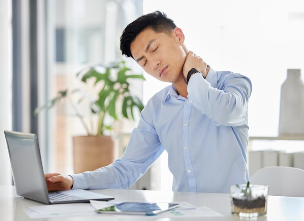 Burnout da stress e dolore al collo Uomo asiatico con mal di testa ansia e depressione che lavora con il laptop sulla dichiarazione fiscale o audit in ufficio Uomo d'affari frustrato e stanco con salute mentale oberato di lavoro