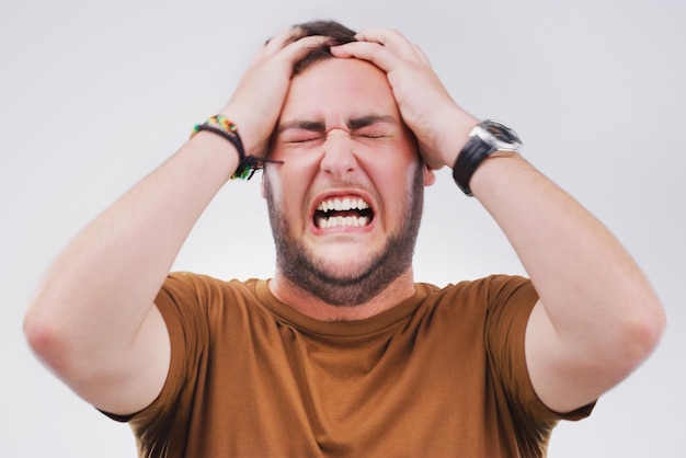 Burnout di rabbia e frustrazione con l'uomo infastidito in studio isolato su sfondo grigio per la reazione Emozione rabbia e stress per il fallimento con il giovane che si sente sconvolto per un incidente fallimento o errore
