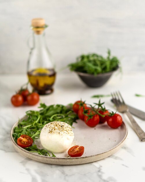 Burrata con rucola, pomodoro, ciliegio e spezie, olio d'oliva, primo piano del cibo nel piatto sulla tavola