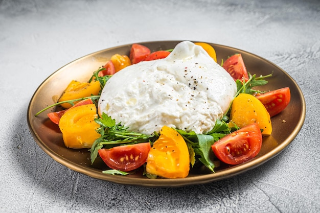 Burrata italiana con pomodorini e rucola fresca Sfondo bianco Vista dall'alto