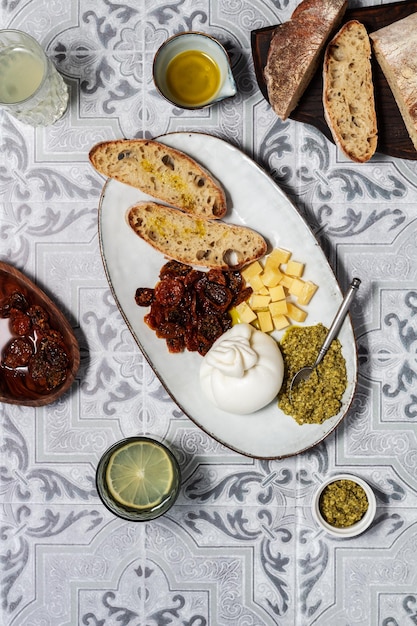 burrata su un piatto con pane, pesto e pomodori secchi