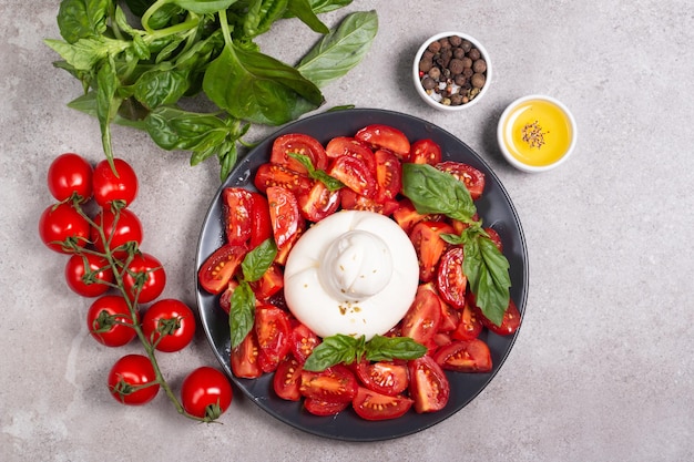 Burrata tradizionale italiana con insalata di delizioso pomodoro ciliegino, foglie di basilico e olio d'oliva