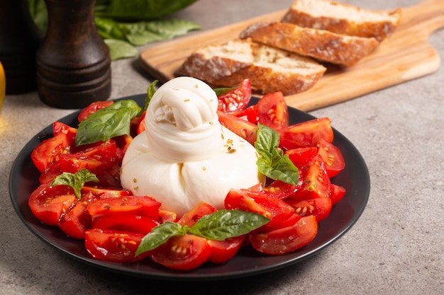 Burrata tradizionale italiana con insalata di delizioso pomodoro ciliegino, foglie di basilico e olio d'oliva