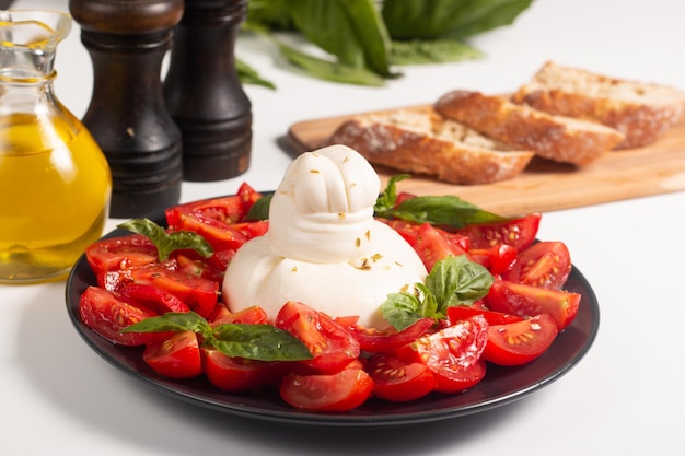 Burrata tradizionale italiana con insalata di delizioso pomodoro ciliegino, foglie di basilico e olio d'oliva