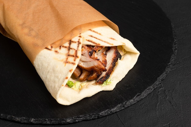 Burrito di pollo Burrito messicano su sfondo nero vista laterale