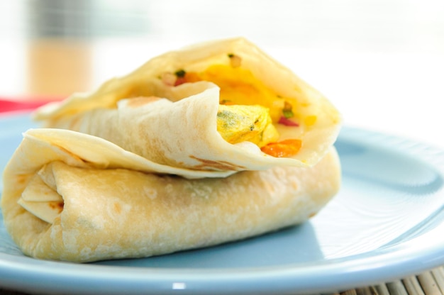 Burrito per la colazione con uova strapazzate con pomodori e cipolla verde