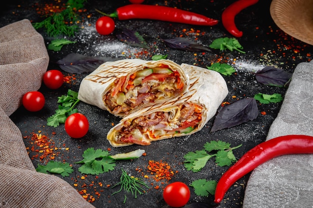 Burrito Shawarma tagliato con verdure ed erbe aromatiche su un tavolo di pietra scuro Il concetto di fast food
