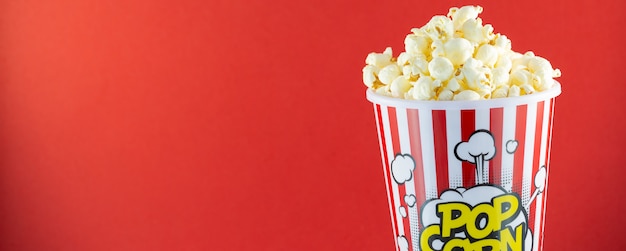 Burro di popcorn in una tazza di popcorn rosso, spuntino in casa o cinema