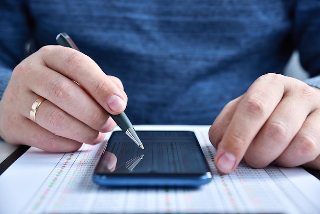 Busiessman con la penna in mano utilizzando il telefono cellulare